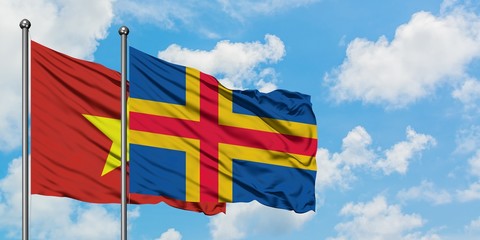 Vietnam and Aland Islands flag waving in the wind against white cloudy blue sky together. Diplomacy...