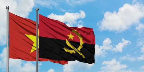 Vietnam and Angola flag waving in the wind against white cloudy blue sky together. Diplomacy...