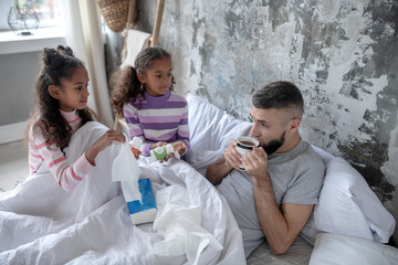 Daughters bringing hot tea and vitamins for their sick daddy