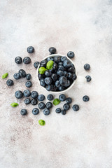 Blueberries lie in a Cup and scattered on a concrete table. Summer seasonal product. Healthy vegetarian dessert. Top view