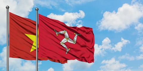 Vietnam and Isle Of Man flag waving in the wind against white cloudy blue sky together. Diplomacy concept, international relations.