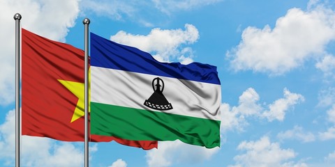 Vietnam and Lesotho flag waving in the wind against white cloudy blue sky together. Diplomacy...