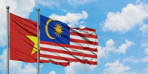 Vietnam and Malaysia flag waving in the wind against white cloudy blue sky together. Diplomacy concept, international relations.