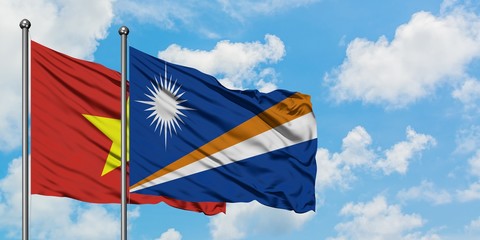 Vietnam and Marshall Islands flag waving in the wind against white cloudy blue sky together. Diplomacy concept, international relations.