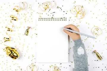 Child's hand writing in notebook on white rustic sparkling background, flat lay style. Christmas...