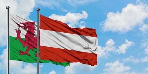 Wales and Austria flag waving in the wind against white cloudy blue sky together. Diplomacy concept, international relations.