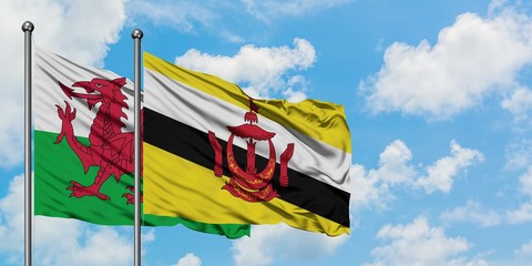 Wales and Brunei flag waving in the wind against white cloudy blue sky together. Diplomacy concept, international relations.