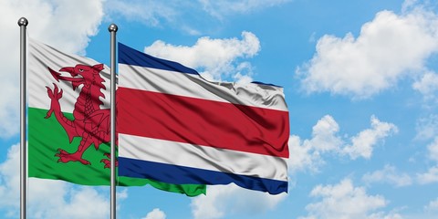 Wales and Costa Rica flag waving in the wind against white cloudy blue sky together. Diplomacy concept, international relations.