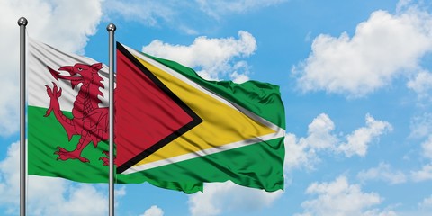 Wales and Guyana flag waving in the wind against white cloudy blue sky together. Diplomacy concept, international relations.