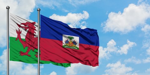 Wales and Haiti flag waving in the wind against white cloudy blue sky together. Diplomacy concept, international relations.