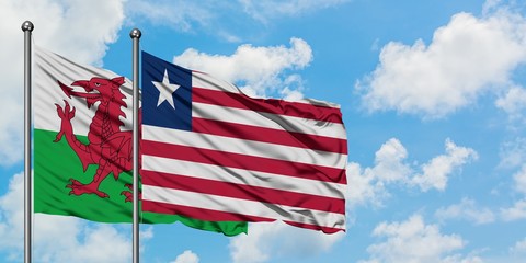 Wales and Liberia flag waving in the wind against white cloudy blue sky together. Diplomacy concept, international relations.