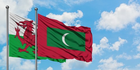 Wales and Maldives flag waving in the wind against white cloudy blue sky together. Diplomacy...