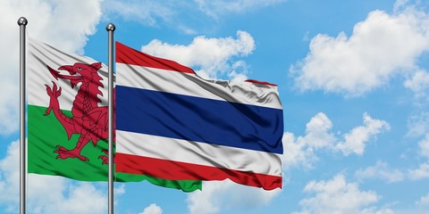 Wales and Thailand flag waving in the wind against white cloudy blue sky together. Diplomacy concept, international relations.