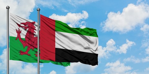 Wales and United Arab Emirates flag waving in the wind against white cloudy blue sky together. Diplomacy concept, international relations.