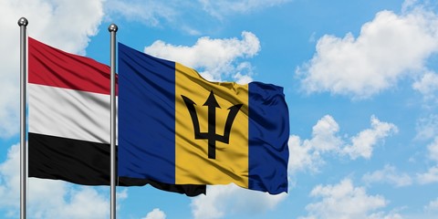 Yemen and Barbados flag waving in the wind against white cloudy blue sky together. Diplomacy concept, international relations.