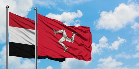 Yemen and Isle Of Man flag waving in the wind against white cloudy blue sky together. Diplomacy concept, international relations.