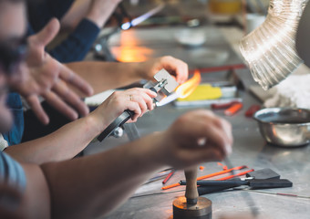 Students at work in a glass-blowing workshop. Glass on fire.