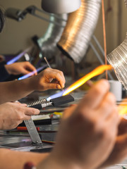 Students at work in a glass-blowing workshop. Glass on fire.