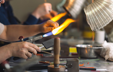 Students at work in a glass-blowing workshop. Glass on fire.