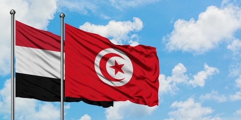 Yemen and Tunisia flag waving in the wind against white cloudy blue sky together. Diplomacy...