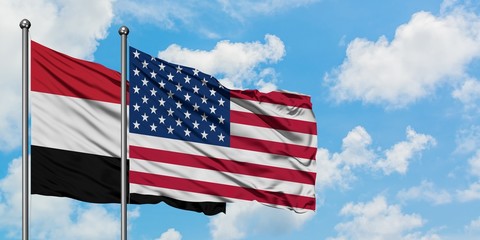 Obraz premium Yemen and United States flag waving in the wind against white cloudy blue sky together. Diplomacy concept, international relations.