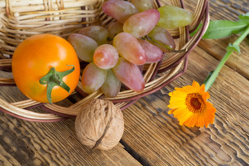 Walnut, tomato and flowers over the wooden natural background.