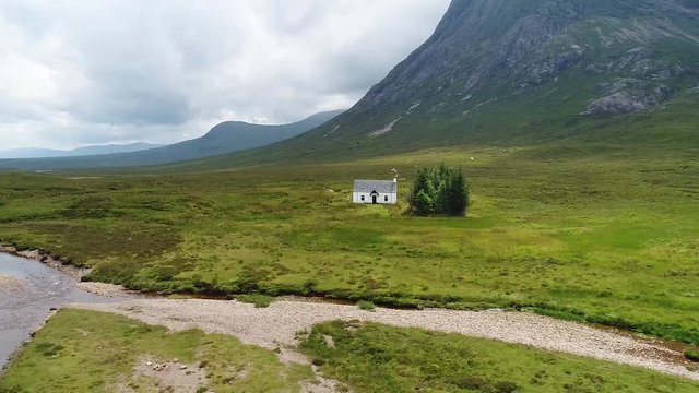 A small cottage in the glencoe valley filmed from above with drone. The lonely house is very close to the river.