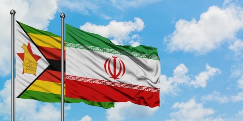 Zimbabwe and Iran flag waving in the wind against white cloudy blue sky together. Diplomacy concept, international relations.