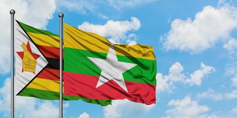 Zimbabwe and Myanmar flag waving in the wind against white cloudy blue sky together. Diplomacy concept, international relations.