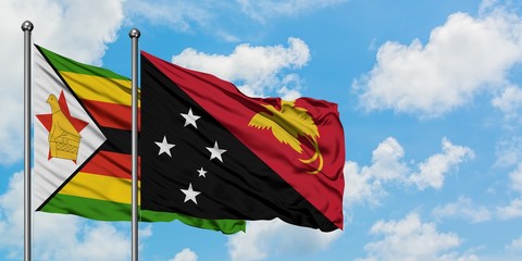 Zimbabwe and Papua New Guinea flag waving in the wind against white cloudy blue sky together. Diplomacy concept, international relations.
