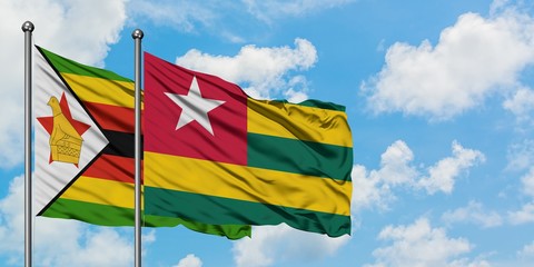 Zimbabwe and Togo flag waving in the wind against white cloudy blue sky together. Diplomacy concept, international relations.