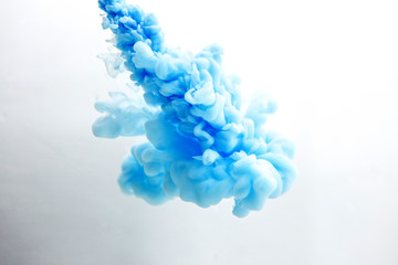 Abstract flowing liquid or blue ink in water on a white background. It looks like smoke or cloud....