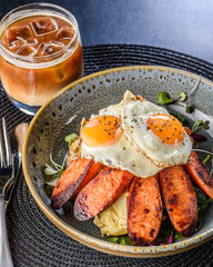 German Potato Salad with fried eggs and Chorizo in a blue bowl.