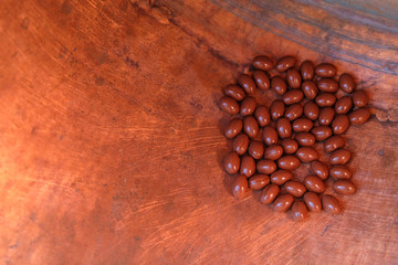 Brown oval pills on copper background. Close up. Copy space.