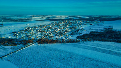 aerial view village among the fields and forests in winter. winter landscape snow covered field and trees in countryside.