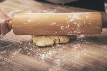 Woman is rolling fresh cookie dough with a dough roll, concept homemade bakery