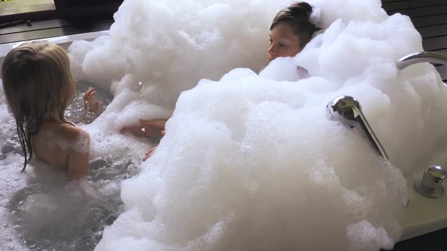 Close up view Two happy children playing in the jacuzzi with soap foam on the luxury villa in Ubud, Bali, Indonesia.