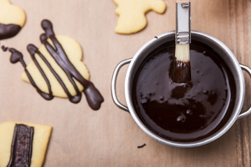 Flatlay, pot with dark liquid chocolate and brigh cookies or biscuits