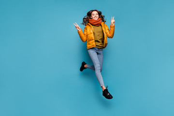 Full body photo of amazing model lady jumping high excited showing v-sign symbol wear stylish windbreaker jeans scarf sweater isolated blue color background © deagreez