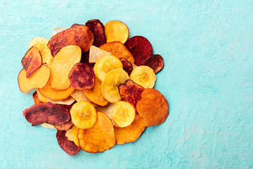 Dried fruit and vegetable chips, healthy vegan snack, a mixed heap on a teal background, top shot with a place for text