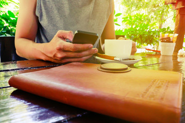 A man Sit on a chair on coffee shop and text messaging with her mobile, hands close up