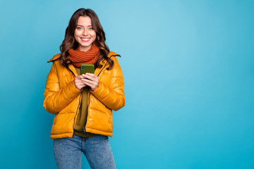 Photo of pretty millennial lady holding telephone checking followers subscribers wear autumn windbreaker jeans scarf pullover isolated blue color background