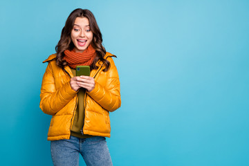 Photo of pretty millennial lady hold telephone read positive comments enjoy followers wear stylish autumn windbreaker jeans scarf isolated blue color background