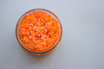Fototapeta na wymiar Red caviar frozen in the refrigerator in a glass jar on a gray background