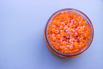 Frozen red caviar in a glass jar on a gray background