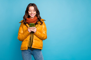 Photo of pretty millennial lady holding telephone reading positive comments blog wear stylish autumn windbreaker jeans scarf pullover isolated blue color background