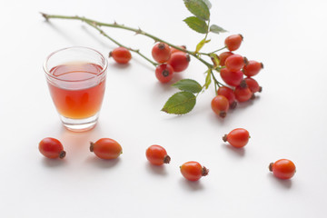 Autumn composition with red rose-hips on white table background and rose-hip liqueur.Fall design.