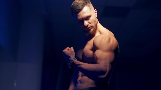 Man posing in gym. Handsome mature man standing strong in the gym and flexing muscles