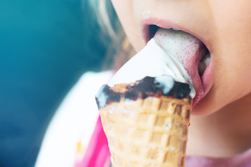 Little girl licks ice cream in waffle cone