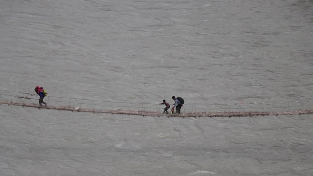 local people crossing the weak twig log bridge in a remote village of zanskar ladakh.